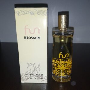 Флакон на тоалетна вода Fun Blossom със златиста капачка и прозрачен дизайн, до светла елегантна опаковка върху дървена повърхност.