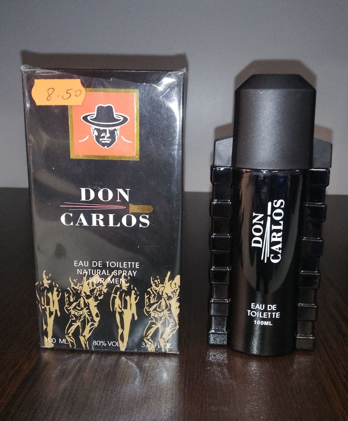 Парфюм "Don Carlos" с черен флакон и стилна опаковка със златни графики, поставен върху тъмен плот. Подходящ за мъже с изискан вкус.